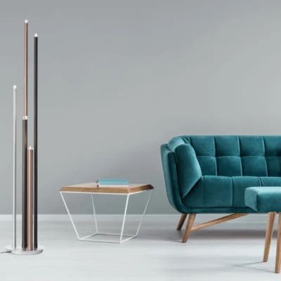 Choix lampadaire Cembalo marque Brilliant, installé à côté d'un canapé bleu canard