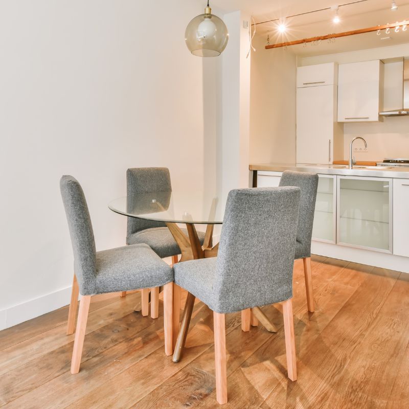 Table en verre avec des chaises autour pour illustrer les avantages et inconvénients de ce type de meuble