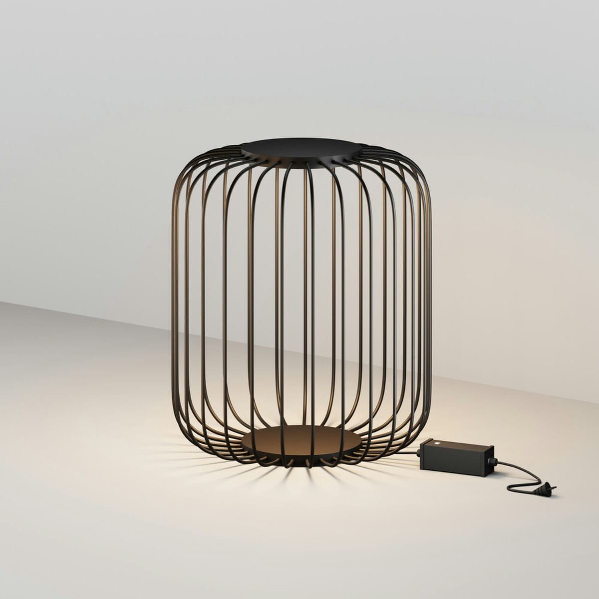 Lampe de table design avec une structure en lignes métalliques courbes, forme de cage cylindrique et plaque de base sombre, câble et bloc d’alimentation visibles. Intègre des matériaux résistants à la corrosion marine.