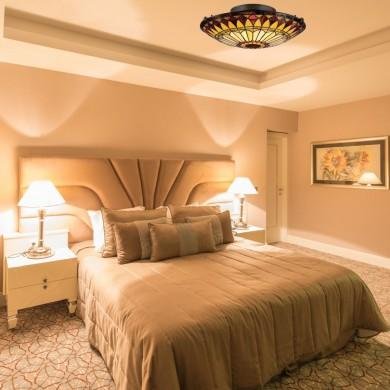 Lits d’hôtel avec lumière chaleureuse, appliques et lampes de chevet créant un éclairage chambre d'hôtel douillet sur une tête de lit padded et plafond lumineux.