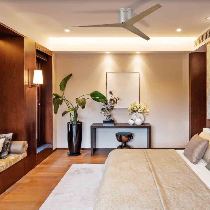 Un loft-chambre moderne avec ventilateur de plafond silencieux au centre, lit beige, bureau sombre et plantes vertes.