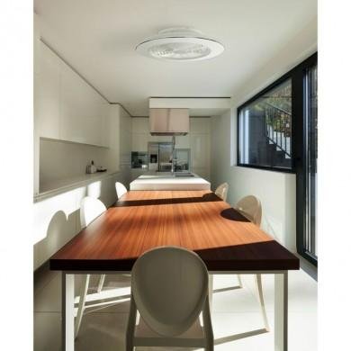 Table à manger en bois sombre dans une cuisine lumineuse, sans pales visibles, plafond rond et fenêtre grande côté droite.