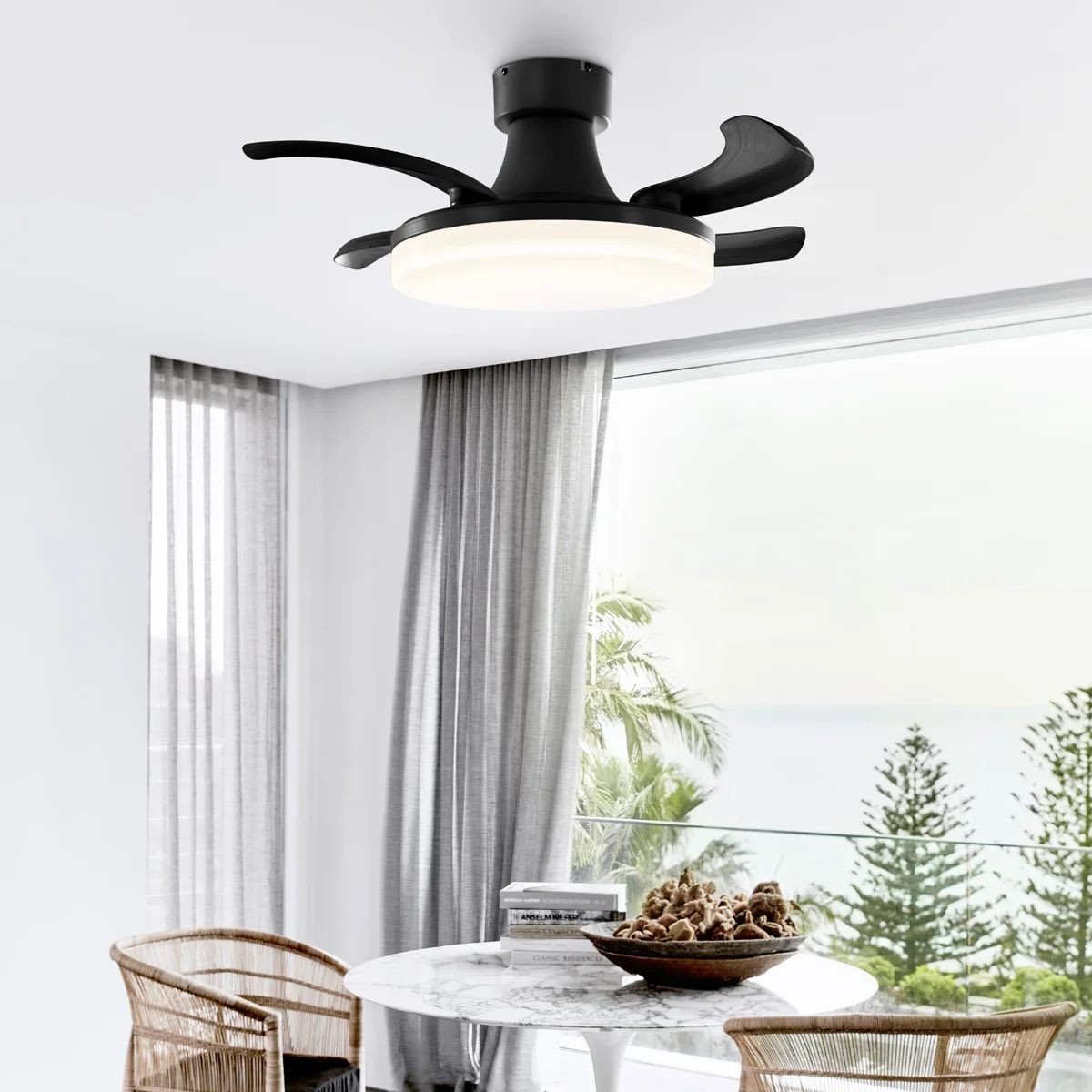 Ventilateur plafond moderne noir avec lumière LED intégré, installé dans un séjour lumineux près d’un mur fenêtre donnant sur l’extérieur.